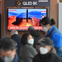 People watch a television showing a news broadcast with file footage of a North Korean missile test, at the main railway station in Seoul on Feb. 27. | AFP-JIJI