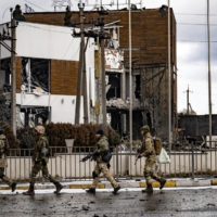 Ukrainian soldiers patrol the bridge linking the city of Irpin with Kyiv on Tuesday.  | LYNSEY ADDARIO / THE NEW YORK TIMES
