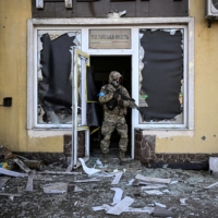 A Ukrainian serviceman exits a damaged building after shelling in Kyiv on Saturday. | AFP-JIJI