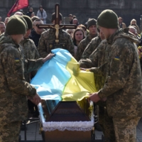 Servicemen cover a coffin with a Ukrainian flag during a funeral in the city of Lviv on Tuesday. | AFP-JIJI
