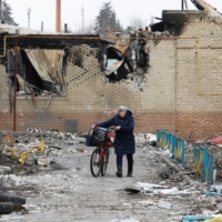 A woman walks next to a building damaged during the Ukraine-Russia conflict in the separatist-controlled town of Volnovakha in the Donetsk region of Ukraine on Tuesday. | REUTERS