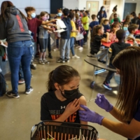 Phoebee Curtis, 9, receives a COVID-19 vaccine in Albuquerque, New Mexico, on Nov. 10. Many experts warn that there are quite a few reasons to believe Americans shouldn’t let their guard down regarding COVID-19 just yet. | PAUL RATJE / THE NEW YORK TIMES
