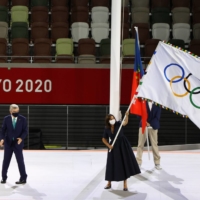 Paris Mayor Anne Hidalgo waves the Olympic flag after receiving it from IOC President Thomas Bach (left) during the closing ceremony of the 2020 Tokyo Games. | REUTERS
