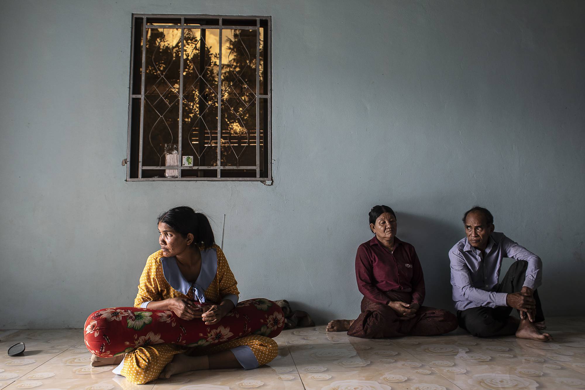 Khuon Savin (left) with her parents in their home in Siem Reap, Cambodia, on Jan. 19. Days before, her husband, Ma Simet, died in a demining accident, Khuon Khai (right) revealed a long-held secret: He had served in the Khmer Rouge. | Nadia Shira Cohen / The New York Times