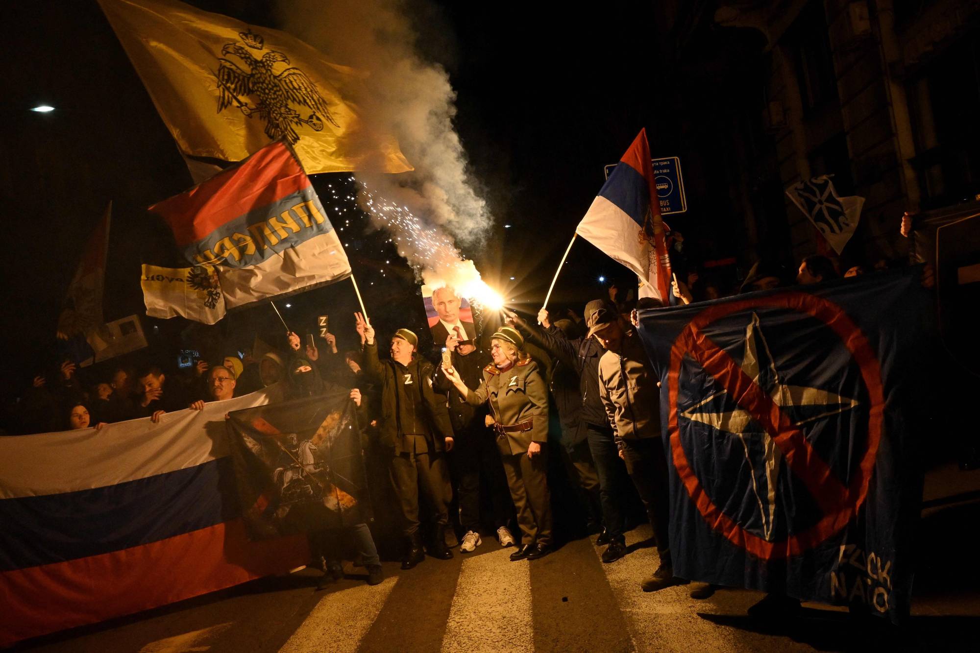 People hold Russian and Serbian flags and a picture of Russian President Vladimir Putin during a rally organized by Serbian right-wing organizations in support of the Russian invasion in Ukraine, in Belgrade on March 4. | AFP-Jiji