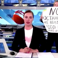 An state TV employee interrupts a live news bulletin on a Russian state television show by holding up a sign that reads \"NO WAR. Stop the war. Don\'t believe propaganda. They are lying to you here\" on March 14 in this screenshot taken from video. | CHANNEL ONE / VIA REUTERS