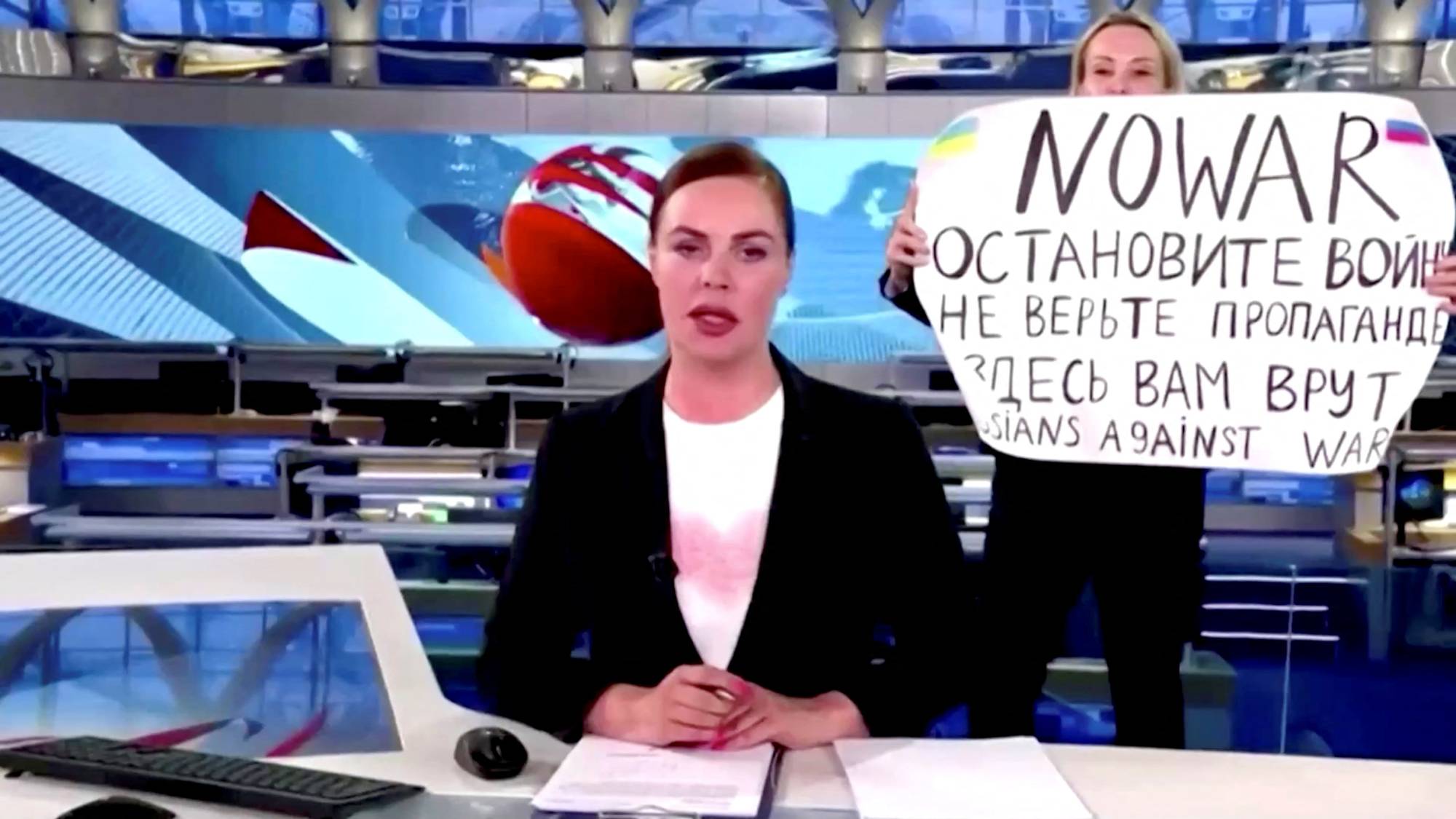 An state TV employee interrupts a live news bulletin on a Russian state television show by holding up a sign that reads 