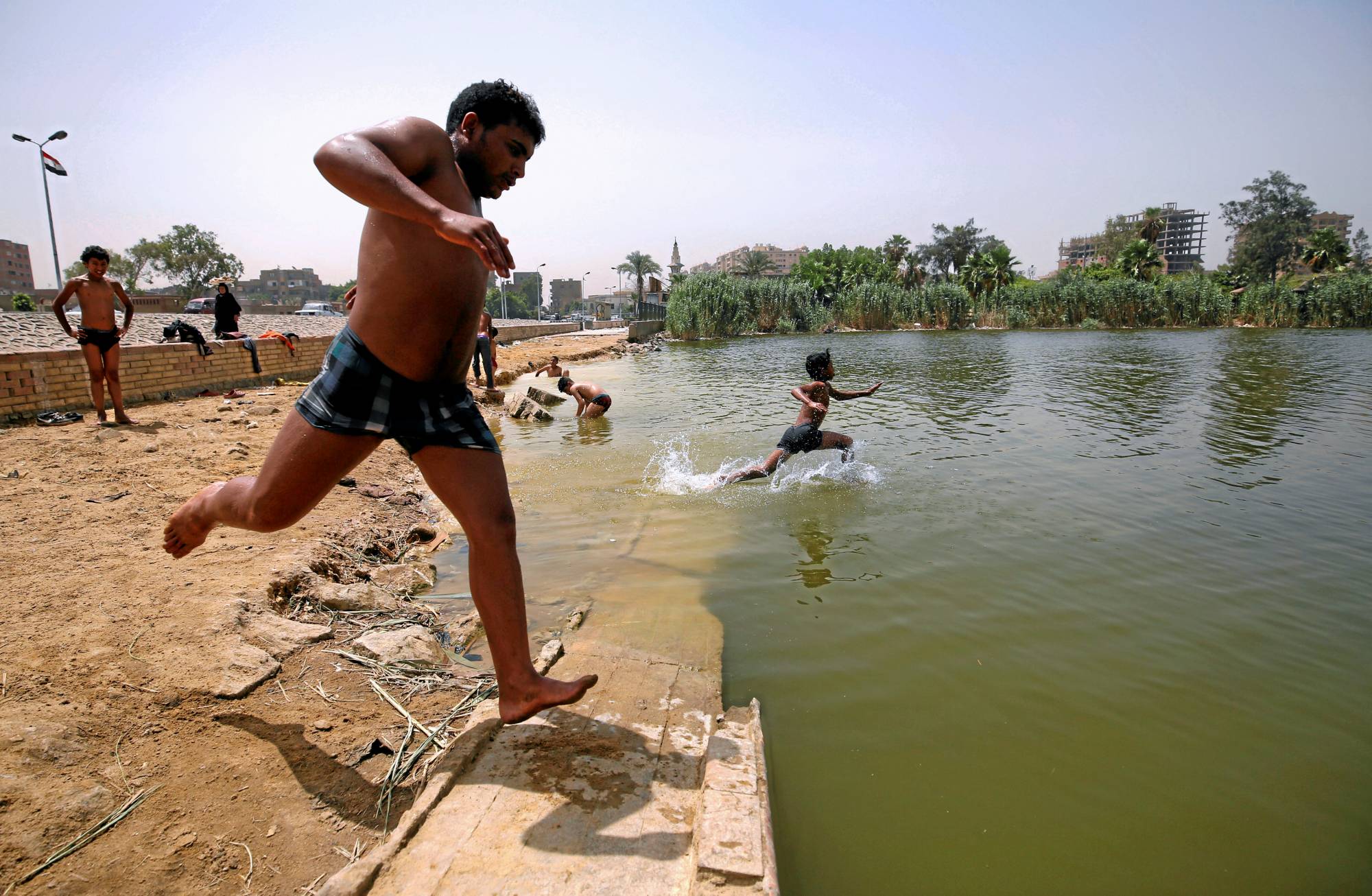 Egyptian boys jump into the Ain El-Sira groundwater lake to cool off on a hot summer day in Old Cairo, Egypt, in 2016. | REUTERS