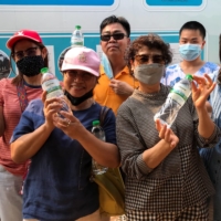 People hold bottles of mineral water from a groundwater spring, accidentally found during groundwater drilling in Kanchanaburi, Thailand, on March 14, 2021. | REUTERS