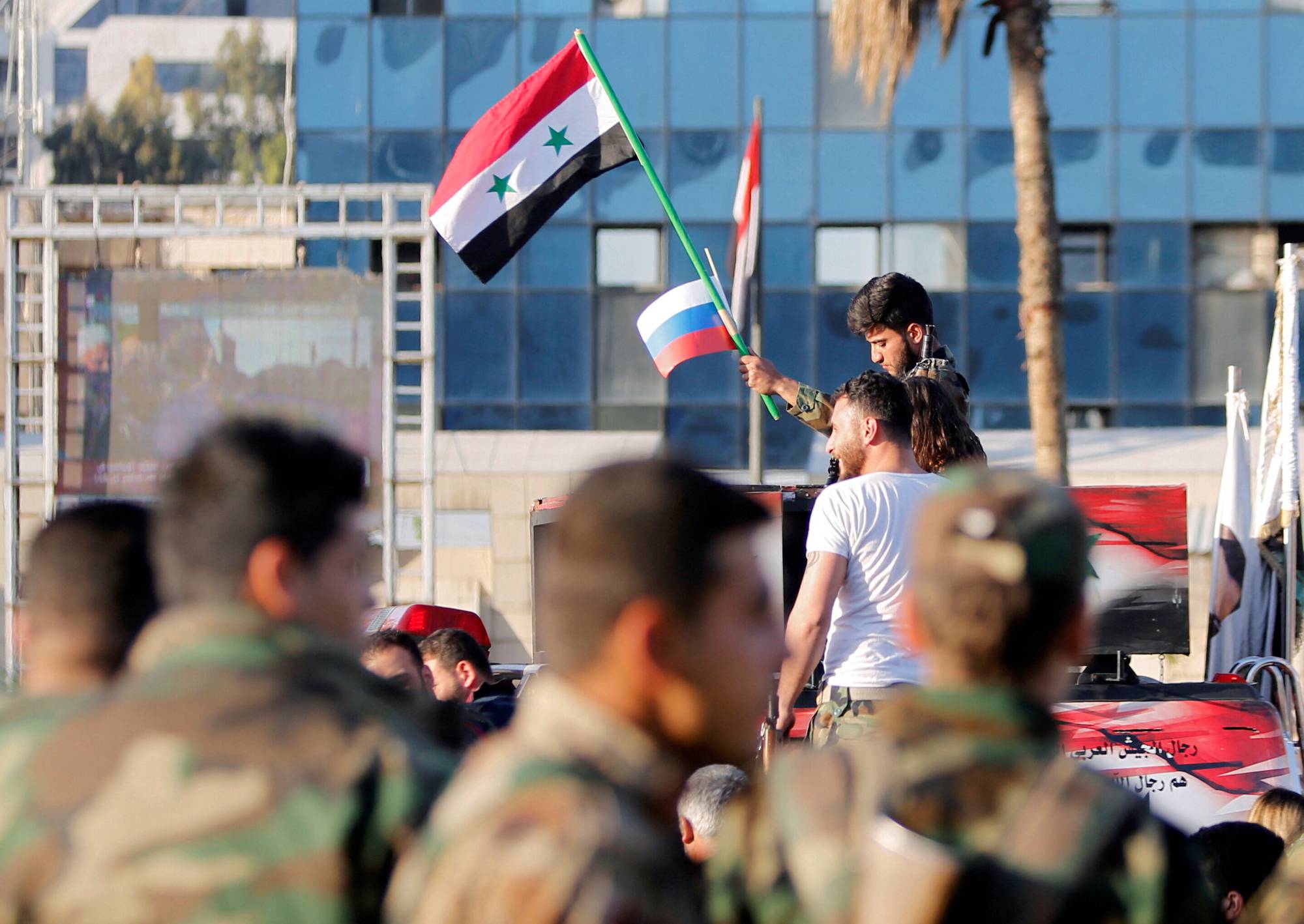 A Syrian soldier waves Russian and Syrian flags during a protest against air strikes in Damascus, Syria, on April 14, 2018. | REUTERS