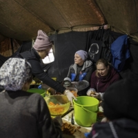 Volunteers prepare food at a market where food is cooked for thousands of people in northern Kyiv, on Tuesday. | LYNSEY ADDARIO / THE NEW YORK TIMES