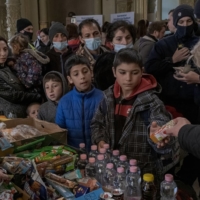 Refugees fleeing the Russian invasion of Ukraine are given food and drinks at a train station in Budapest, Hungary, on March 6. | MAURICIO LIMA / THE NEW YORK TIMES