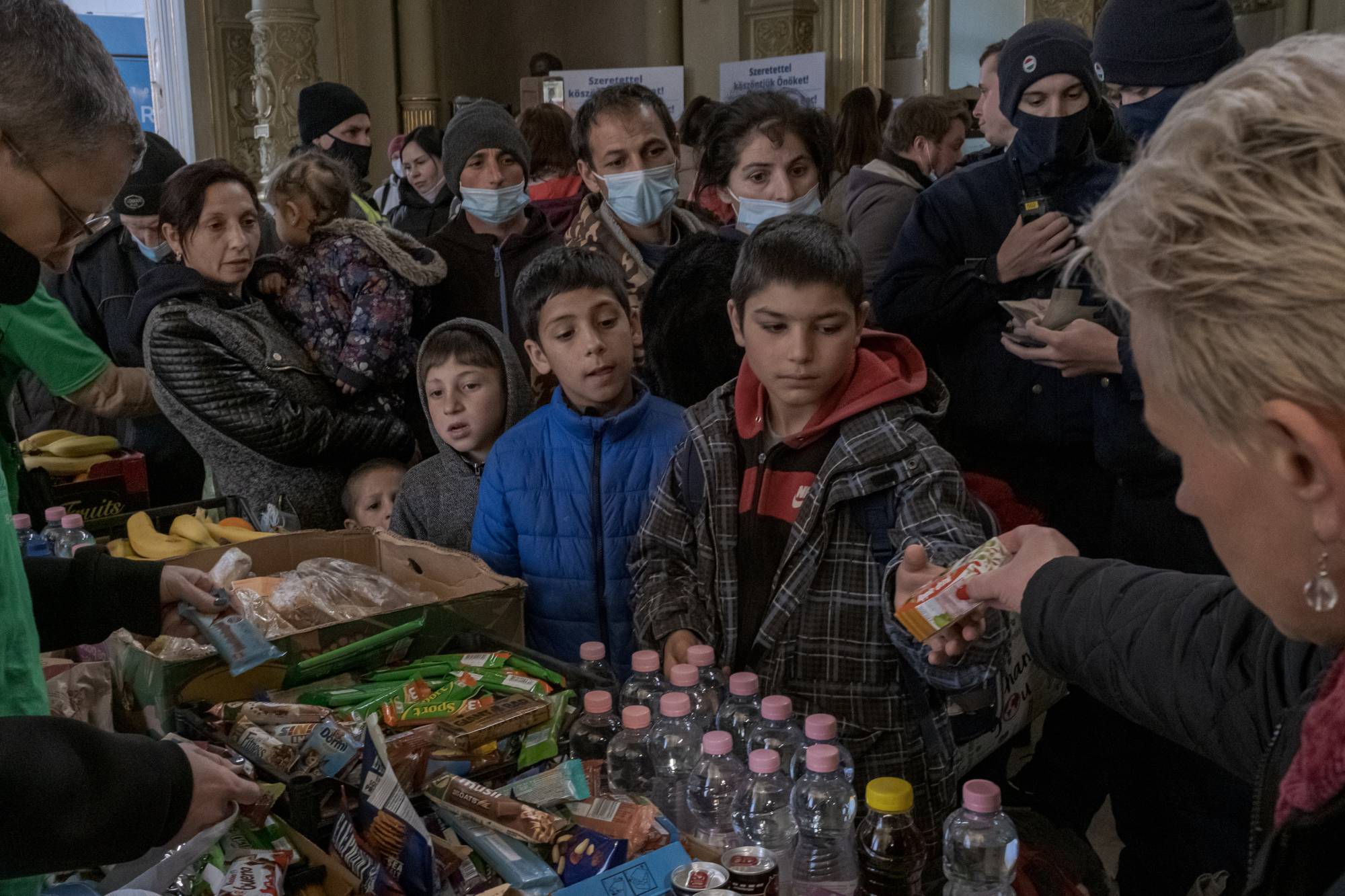 Refugees fleeing the Russian invasion of Ukraine are given food and drinks at a train station in Budapest, Hungary, on March 6. | Mauricio Lima / The New York Times