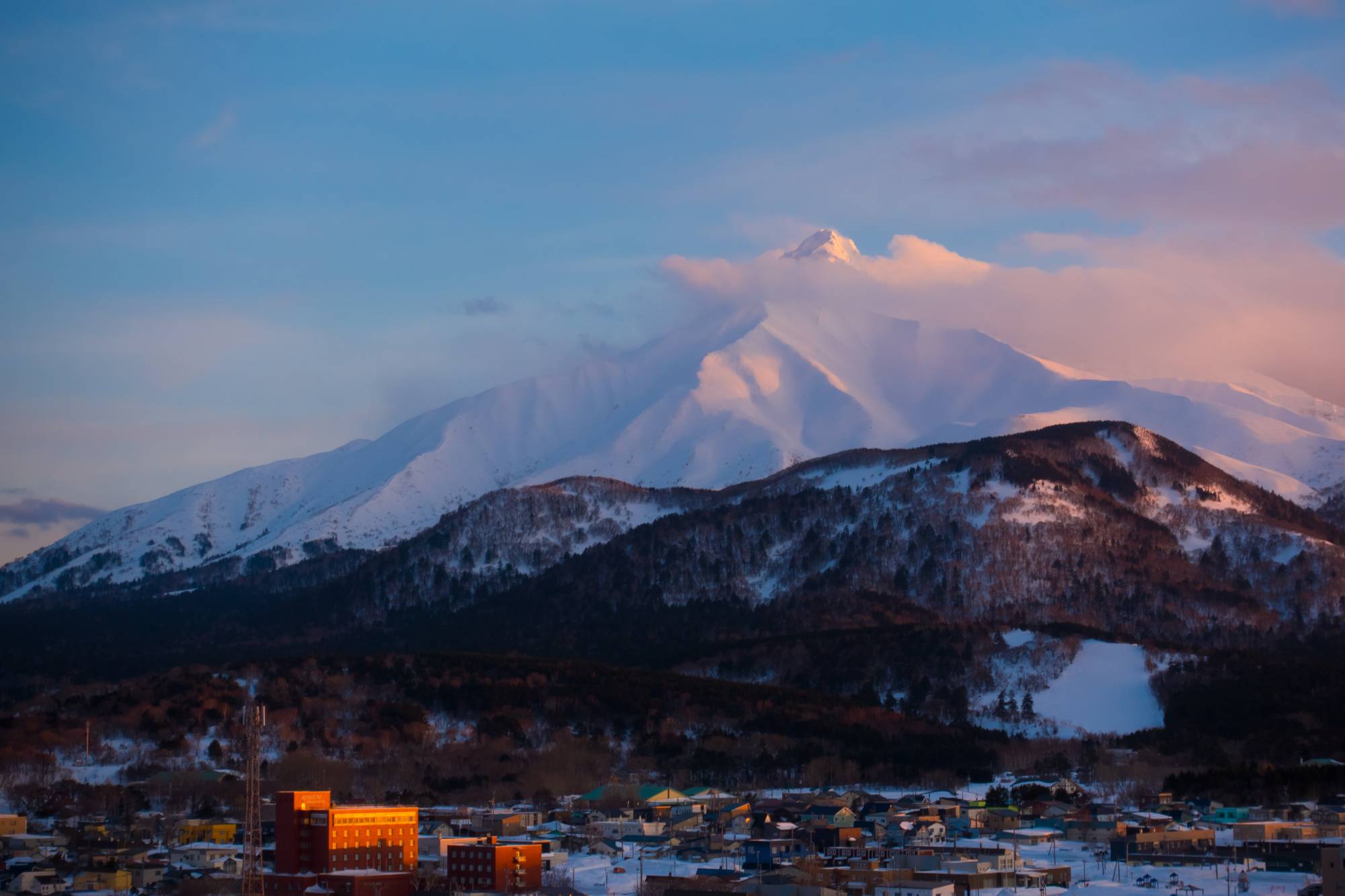 The peak of Mount Rishiri emerges from the clouds at sunset. | OSCAR BOYD