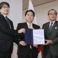 
Nagasaki Mayor Tomihisa Taue (left), Hiroshima Mayor Kazumi Matsui (right) and Foreign Minister Hayashi Yoshimasa hold a request from the two mayors in Tokyo on Tuesday. | KYODO
