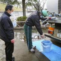 A man gets a bucket filled with water in Sendai on March 17 after the city suffered a water outage following a major earthquake the previous day. | KYODO