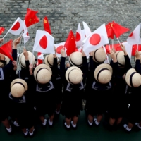Kindergarten pupils wave national flags ahead of talks between Chinese Premier Li Keqiang and then-Prime Minister Shinzo Abe at Akasaka Palace state guest house in Tokyo in May 2018. | REUTERS
