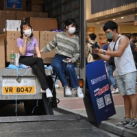 Two women sit in the back of a truck in the Mongkok area of Hong Kong on Saturday.  | AFP-JIJI