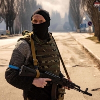 A Ukrainian serviceman stands guard near a burning warehouse hit by a Russian shell in the suburbs of Kyiv on Thursday.. | AFP-JIJI