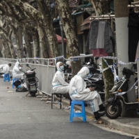 Quarantine workers on a street in a neighborhood that was just put under lockdown for rising COVID-19 cases in Shanghai, China, on March 15. Many Asian-Pacific countries are dismantling thickets of coronavirus pandemic rules at bewildering speeds, with one notable exception: mainland China, which is still rolling out lockdowns. | QILAI SHEN / THE NEW YORK TIMES