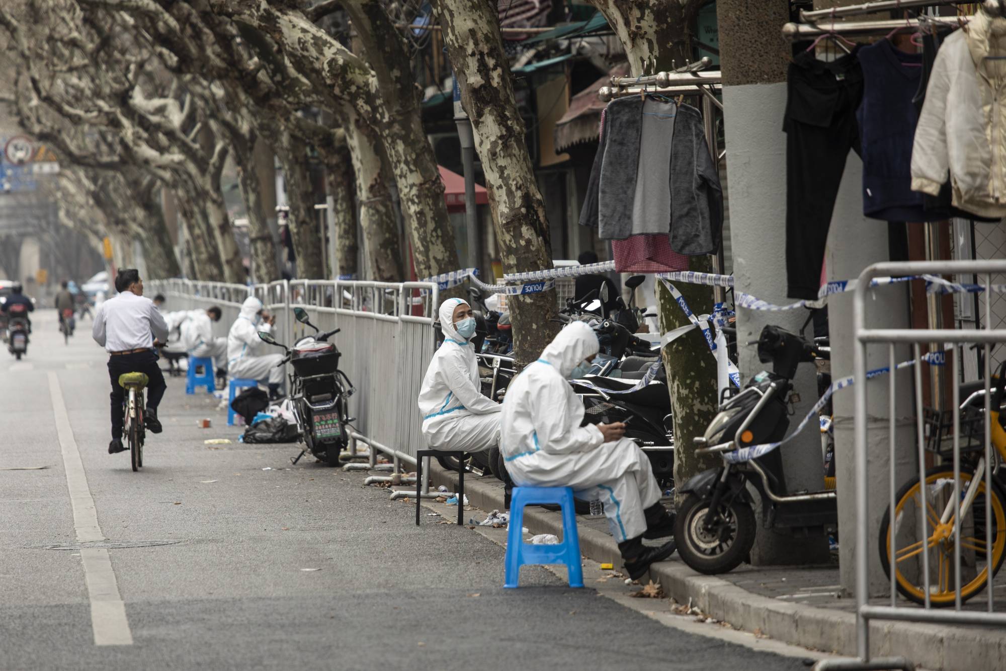 Quarantine workers on a street in a neighborhood that was just put under lockdown for rising COVID-19 cases in Shanghai, China, on March 15. Many Asian-Pacific countries are dismantling thickets of coronavirus pandemic rules at bewildering speeds, with one notable exception: mainland China, which is still rolling out lockdowns. | Qilai Shen / The New York Times