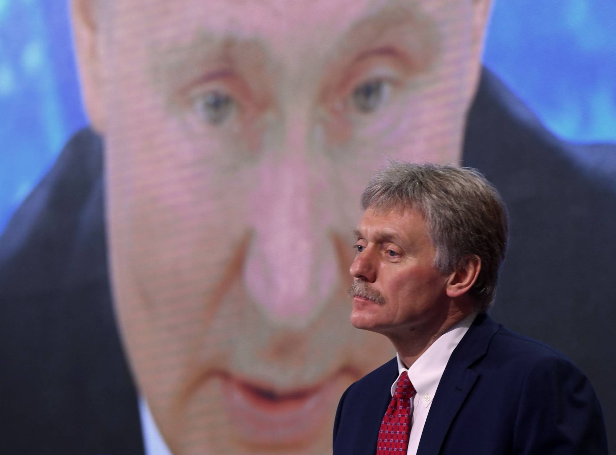 Kremlin spokesman Dmitry Peskov sits in front of a screen displaying Russian President Vladimir Putin. Peskov said last week that Russia would only use nuclear weapons in the context of Ukraine conflict if it were facing an 
