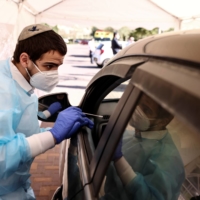 Medical staff carry out tests for COVID-19 at a drive-through site in Jerusalem in January.  | REUTERS 