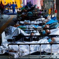 Patients wearing face masks rest at a makeshift treatment area outside a hospital amid the latest coronavirus outbreak in Hong Kong, on March 2. | REUTERS