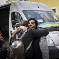 People embrace at an aid station on the outskirts of Kyiv, after evacuating Irpin, Ukraine, on March 24. | IVOR PRICKETT / THE NEW YORK TIMES