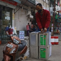 A customer packs canisters of cooking oils purchased from a store in New Delhi. | BLOOMBERG