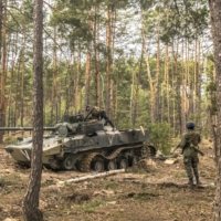 Ukrainian soldiers and foreign fighters survey a destroyed Russian tank during a clearing-out operation of remaining Russian forces in Irpin, Ukraine, on Tuesday. | DANIEL BEREHULAK/THE NEW YORK TIMES