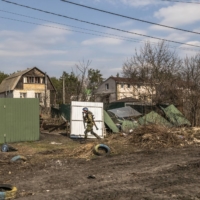 A soldier for Ukraine takes cover as he advances in the streets during a clearing-out operation of remaining Russian forces in Irpin, Ukraine, on Tuesday.  | DANIEL BEREHULAK/THE NEW YORK TIMES