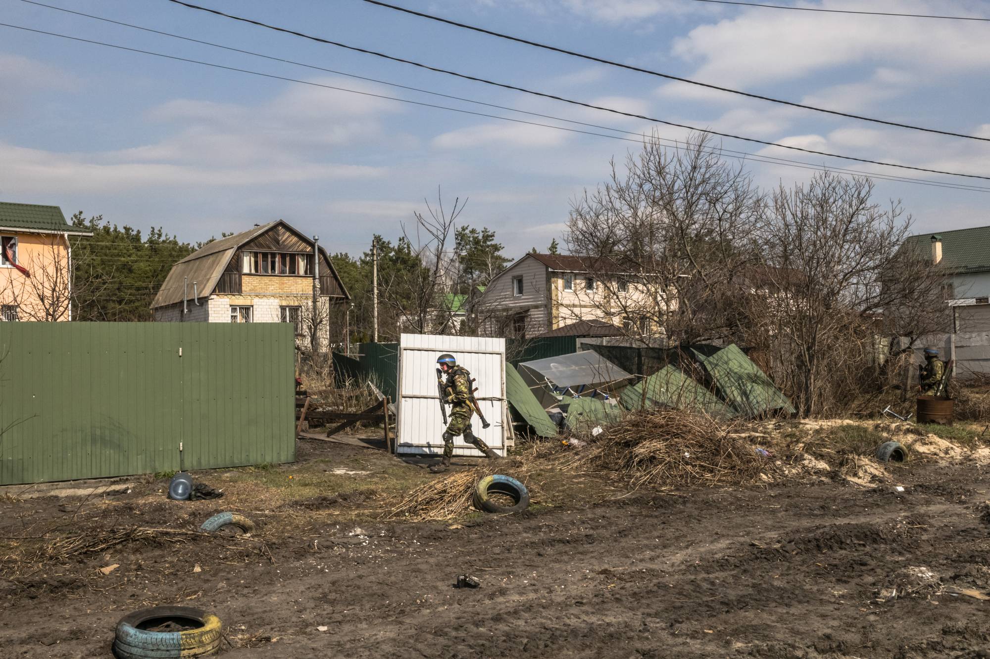 A soldier for Ukraine takes cover as he advances in the streets during a clearing-out operation of remaining Russian forces in Irpin, Ukraine, on Tuesday. | Daniel Berehulak/The New York Times