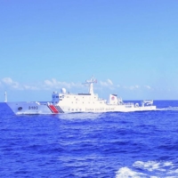 A Philippine coast guard member monitors a China Coast Guard ship shadowing their vessel while conducting a maritime patrol in the Scarborough Shoal in teh South China Sea on  March 2.  | PHILIPPINE COAST GUARD / VIA AFP-JIJI