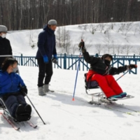 Mana Nakoshi (right) practicing sit-skiing at a course in Sapporo, on March 12. | KYODO