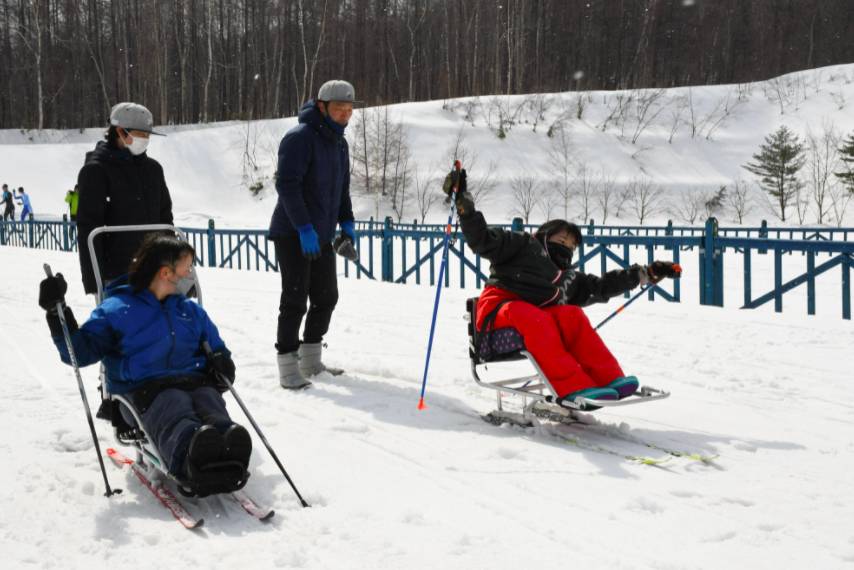 Mana Nakoshi (right) practicing sit-skiing at a course in Sapporo, on March 12. | KYODO