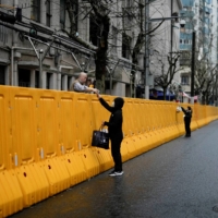 People pass food to residents over the barriers of an area under COVID-19 lockdown in Shanghai, China | REUTERS