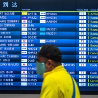 A passenger walks past a flight information board at Haneda Airport in Tokyo on March 2. | AFP-JIJI