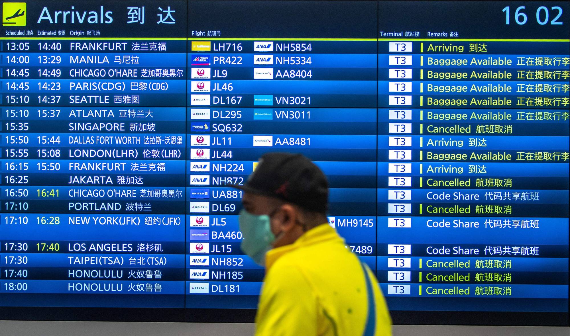 A passenger walks past a flight information board at Haneda Airport in Tokyo on March 2. | AFP-JIJI
