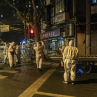 Quarantine workers set up barriers in a Shanghai neighborhood that was put under lockdown last month.  | QILAI SHEN / THE NEW YORK TIMES