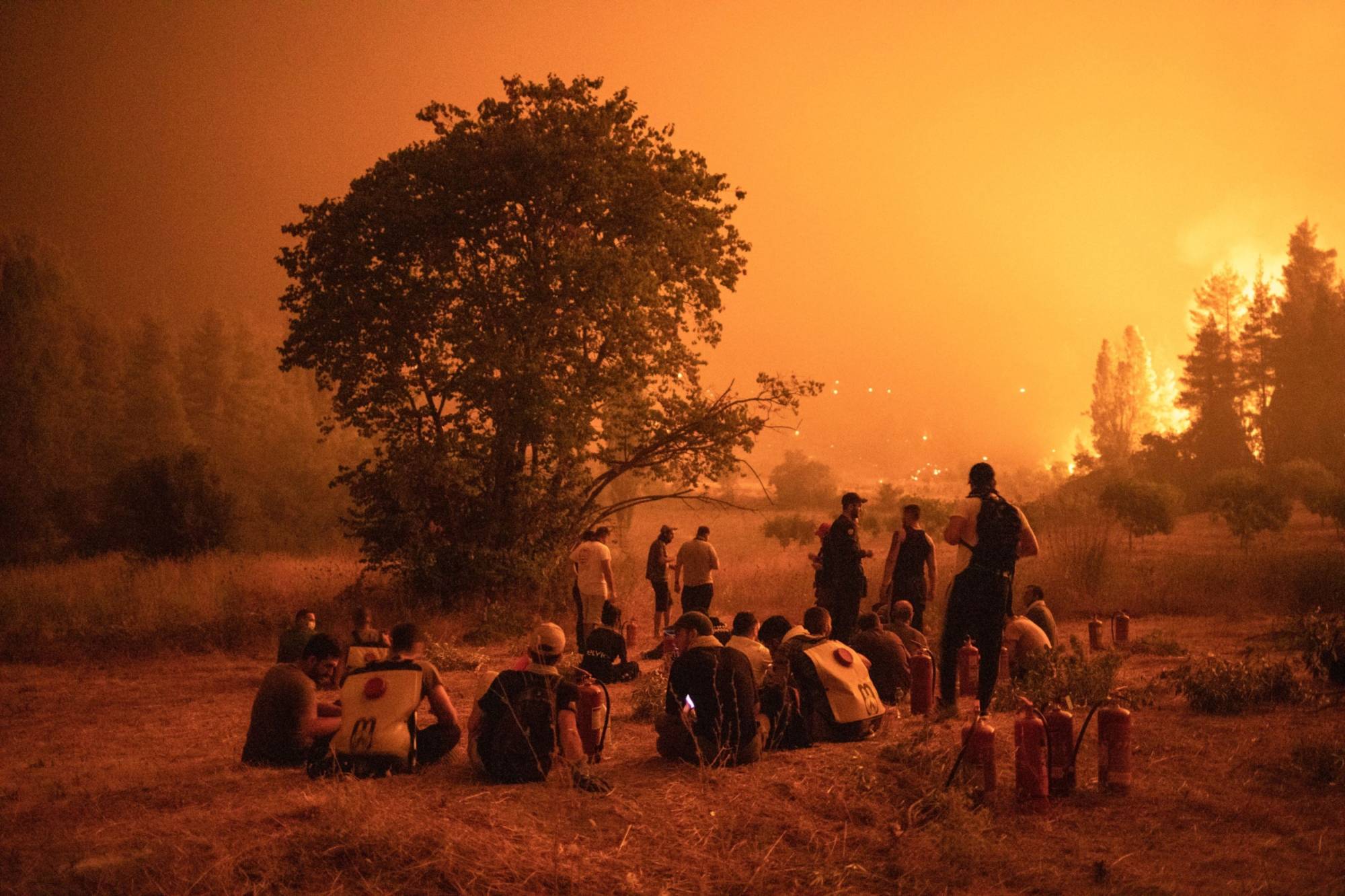 Residents gather to watch over the wildfire and wait to support firefighters outside the village of Kamatriades, on Evia island, Greece, in August. | BLOOMBERG