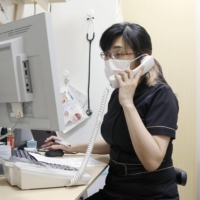 A doctor checks on a COVID-19 patient recuperating at home in Tokyo in February. | KYODO
