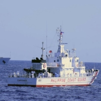 A China Coast Guard ship (left) shadows a Philippine Coast Guard vessel while conducting a maritime patrol near the Scarborough Shoal in the South China Sea on March 2. | PHILIPPINE COAST GUARD / VIA AFP-JIJI