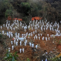 Rescue workers stand in a silent tribute on March 27 at the crash site to mourn the victims of a China Eastern Airlines Boeing 737-800 plane, flight MU5735, that crashed in Wuzhou, China. | REUTERS