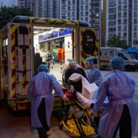 Health care workers transfer a patient to a hospital in Hong Kong on March 2, during the fifth wave of the coronavirus.  | BILLY H.C. KWOK / THE NEW YORK TIMES