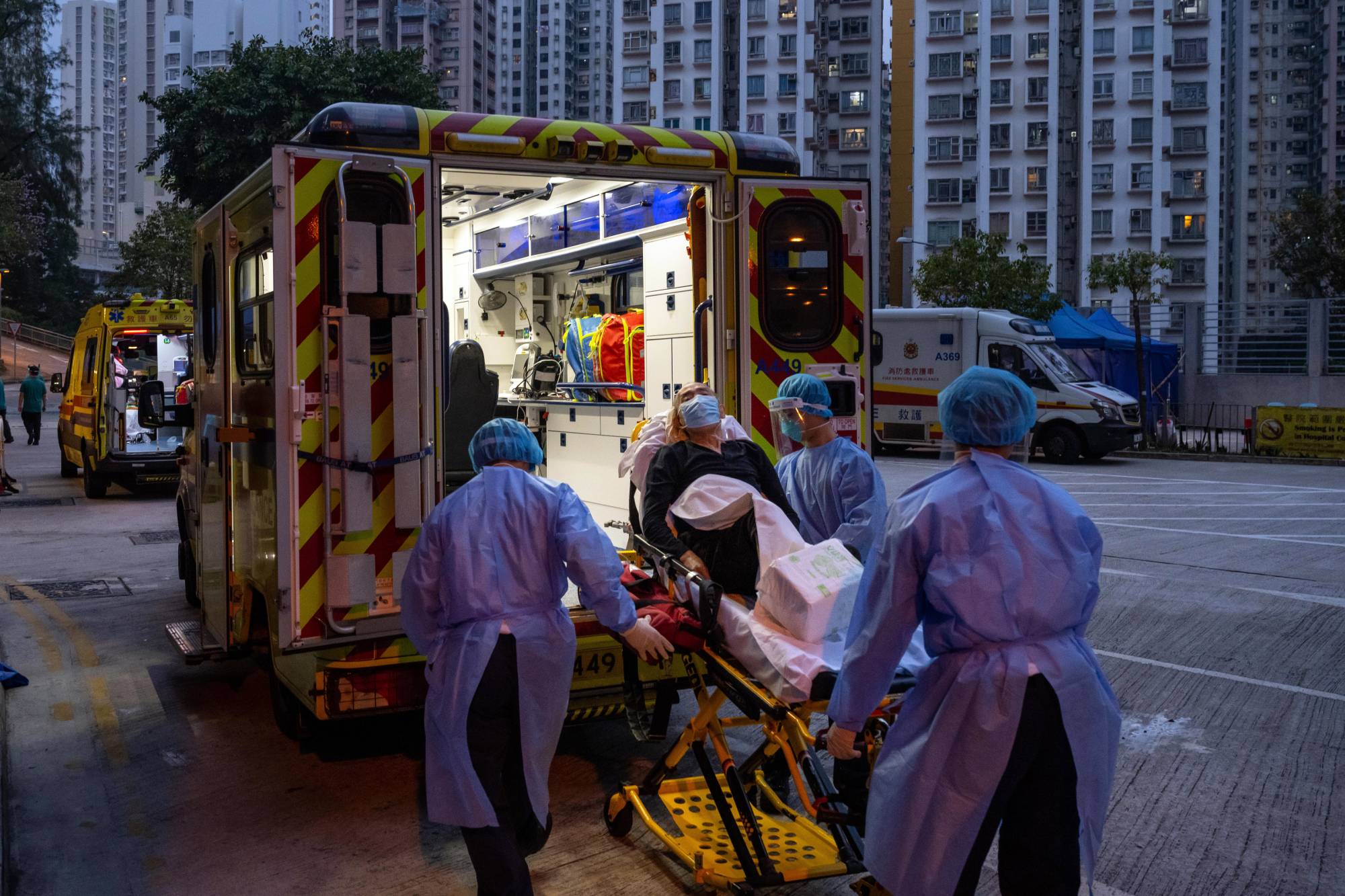 Health care workers transfer a patient to a hospital in Hong Kong on March 2, during the fifth wave of the coronavirus.  | Billy H.C. Kwok / The New York Times