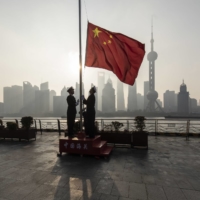 China Customs officers raise a Chinese flag at sunrise during a rehearsal for a flag-raising ceremony along the Bund, in front of buildings in the Lujiazui Financial District in Shanghai, in January. | BLOOMBERG

