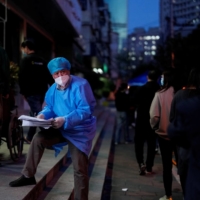 A worker in a protective suit directs residents lining up for nucleic acid test during a lockdown to curb the spread of COVID-19 in Shanghai on Saturday. | REUTERS