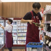 Employees stock shelves at a Seijo Ishii store in Tokyo in September 2017. | BLOOMBERG
