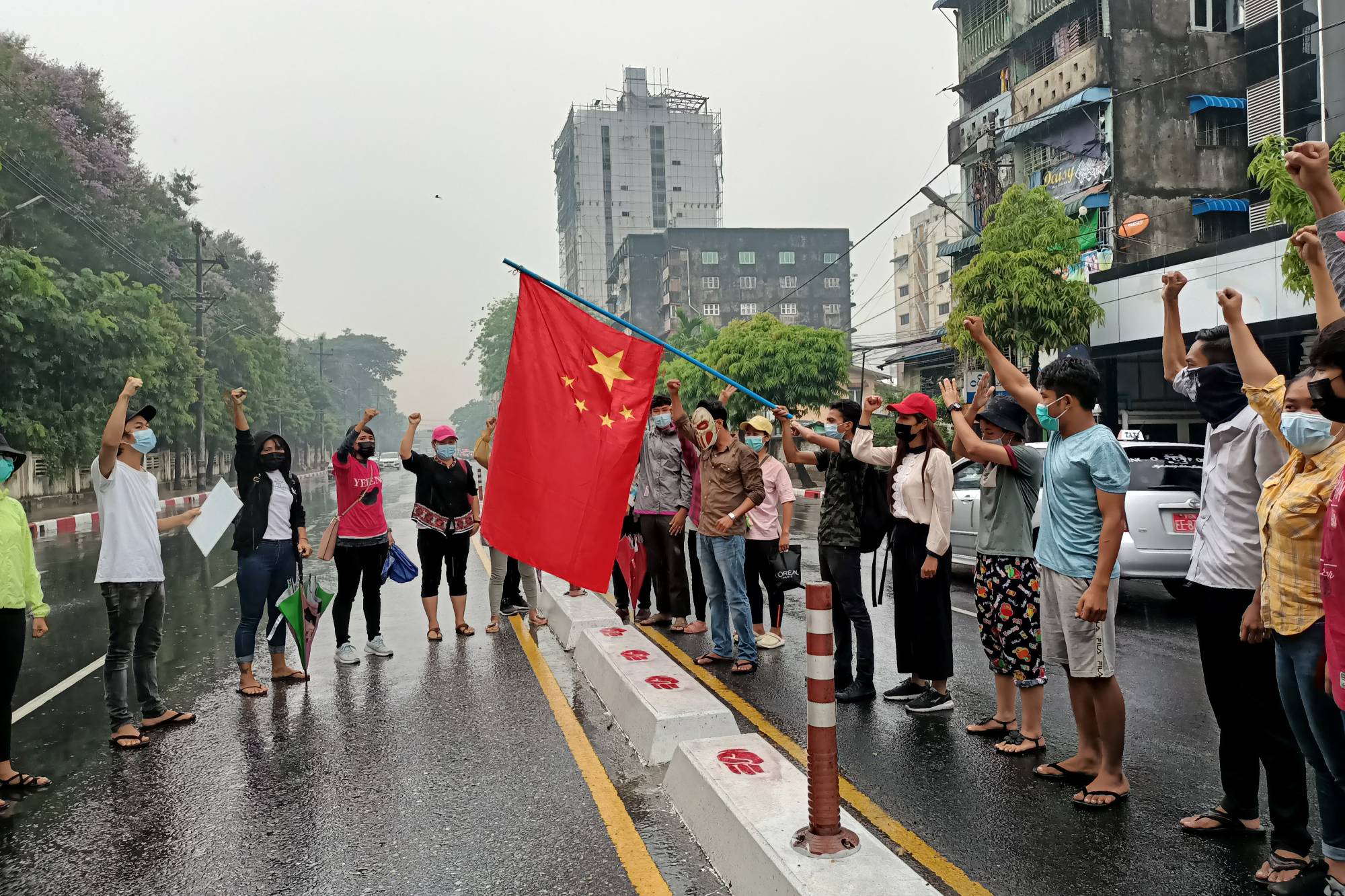 Anti-military coup protesters raise a Chinese flag before burning it during a demonstration against China in Yangon in April 2021. | REUTERS